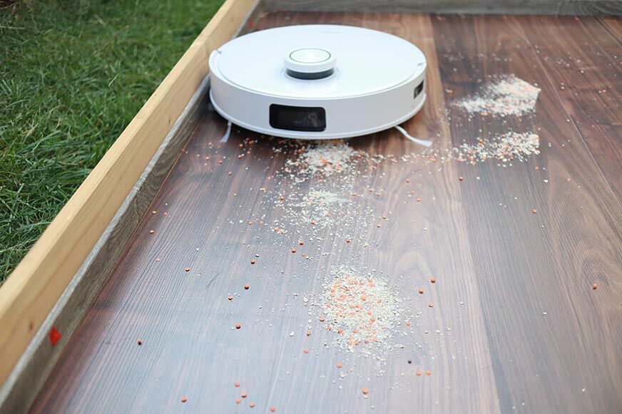 ECOVACS DEEBOT T10 reinigt im Test Haferflocken auf einem Hartboden.